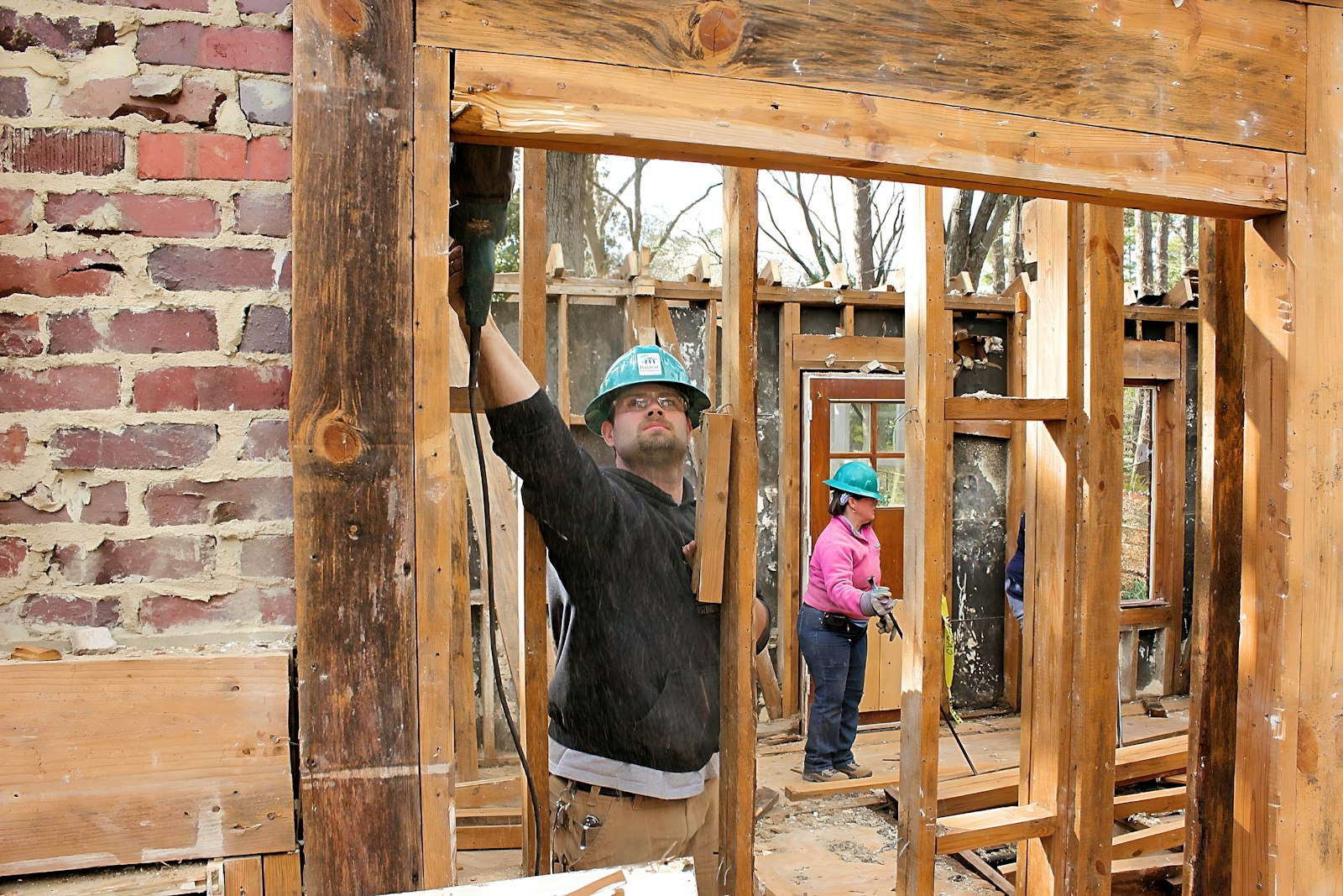 Crew fitting a window into the rough opening of new wall framing