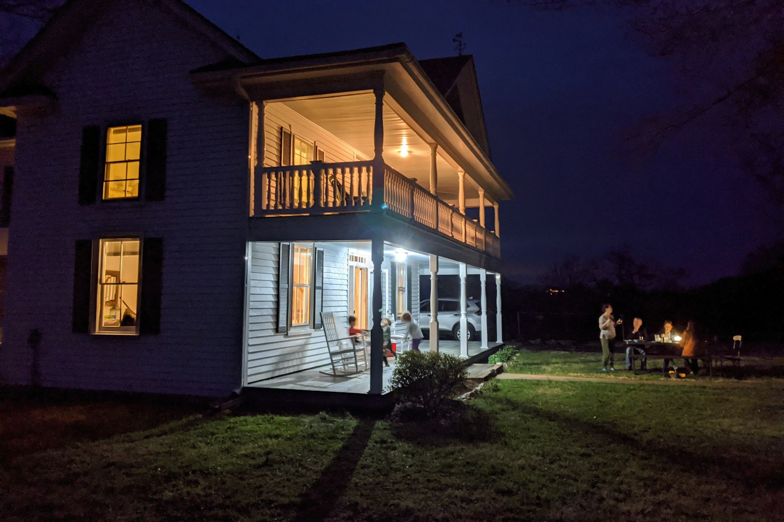Farmhouse porch at evening with warm light in the windows