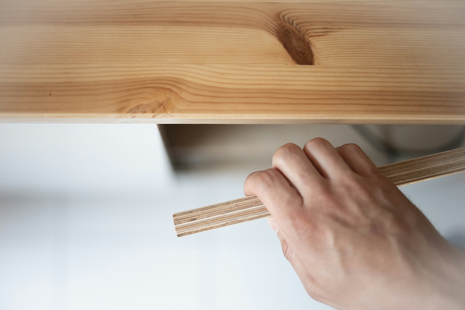 Hands unrolling a set of construction drawings across a plywood sheet on site